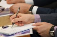 человек в костюме пишет на бумаге ручкой